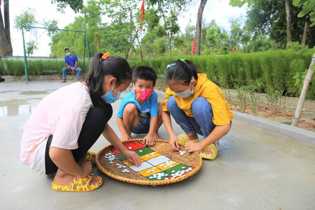 Trẻ em tập trung suy nghĩ các bước đi trên bàn cờ ô ăn quan